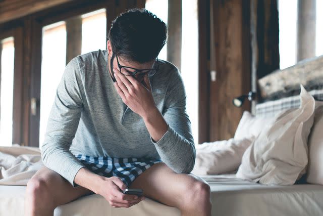 <p>Getty</p> Stock image of a tired individual sitting in bed