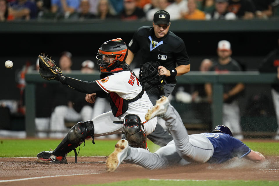 Tampa Bay Rays' Luke Raley, right, slides in ahead of the throw as Baltimore Orioles catcher Adley Rutschman tries to make the out on a ball hit by Brandon Lowe in the third inning of a baseball game, Thursday, Sept. 14, 2023, in Baltimore. (AP Photo/Julio Cortez)