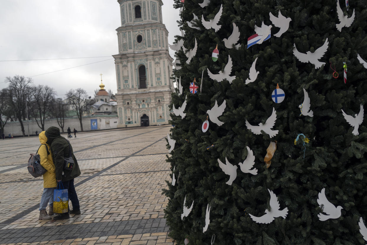 Ukrainian couple kiss each other in front of a Chrismas tree outside the St. Sophia cathedral in Kyiv, Ukraine, Friday, Jan. 6, 2023. Russian President Vladimir Putin on Thursday ordered Moscow's armed forces to observe a 36-hour cease-fire in Ukraine this weekend for the Russian Orthodox Christmas holiday, but Ukrainian President Volodymyr Zelenskyy questioned the Kremlin's intentions, accusing the Kremlin of planning the fighting pause "to continue the war with renewed vigor". (AP Photo/Bela Szandelszky)