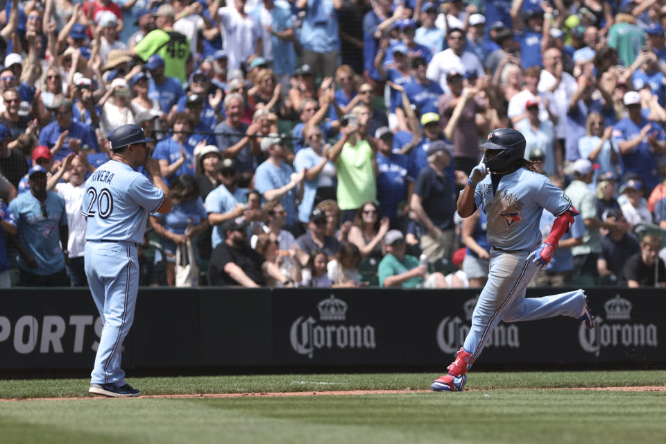 Toronto Blue Jays' Vladimir Guerrero Jr., right, celebrates with third base coach Luis Rivera (20) after hitting a solo home run during the fifth inning of a baseball game against the Seattle Mariners, Saturday, July 22, 2023, in Seattle. (AP Photo/Jason Redmond)