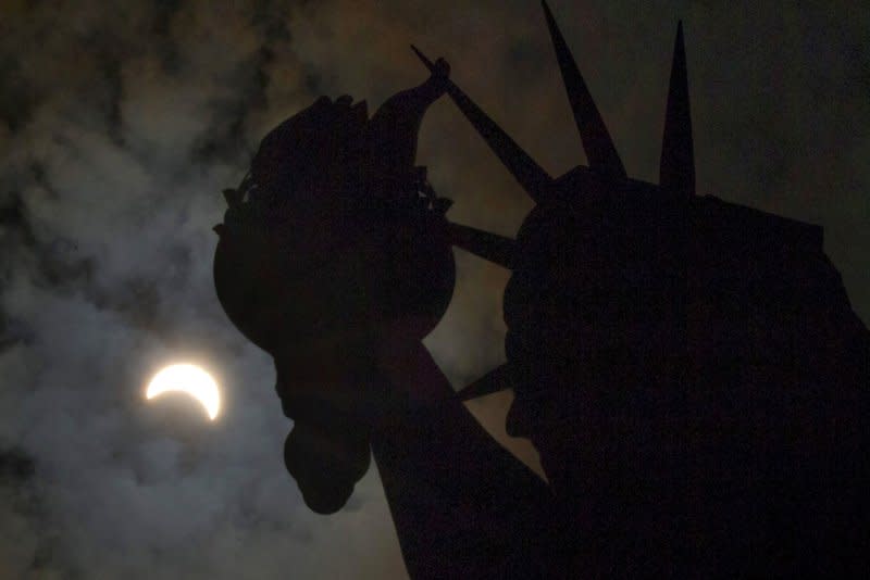 A solar eclipse moves across the sky near the crown and torch of the Statue of Liberty on Liberty Island on August 21, 2017. File Photo by John Angelillo/UPI