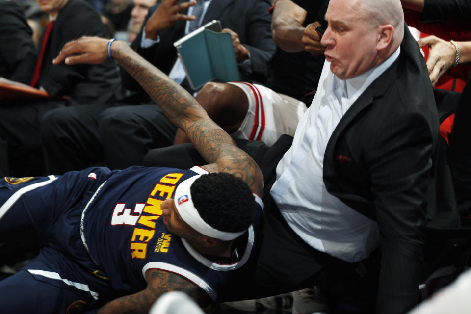 Denver Nuggets forward Torrey Craig, front, lands on Chicago Bulls head coach Jim Boylen while trying to field a cross-court pass from Nuggets center Nikola Jokic in the first half of an NBA basketball game, Thursday, Jan. 17, 2019, in Denver. (AP Photo/David Zalubowski)