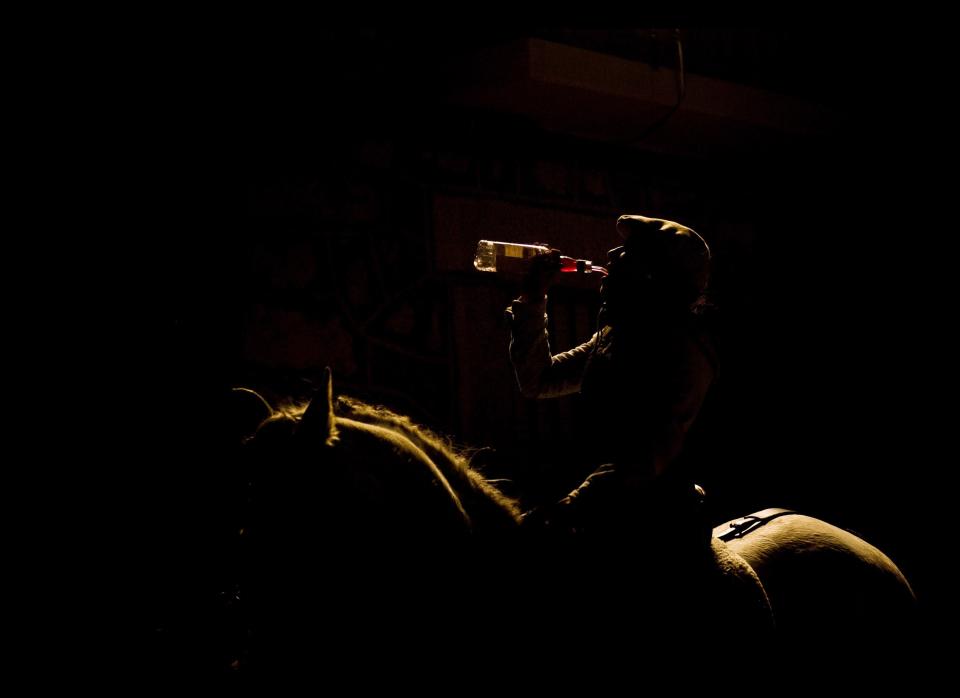 A woman drinks after riding her horse near by bonfires in San Bartolome de Pinares, Spain, Monday, Jan. 16, 2012, in honor of Saint Anthony, the patron saint of animals. On the eve of Saint Anthony's Day, hundreds ride their horses trough the narrow cobblestone streets of the small village of San Bartolome during the 'Luminarias' a tradition that dates back 500 years and is meant to purify the animals with the smoke of the bonfires and protect them for the year to come. (Daniel Ochoa de Olza, AP)