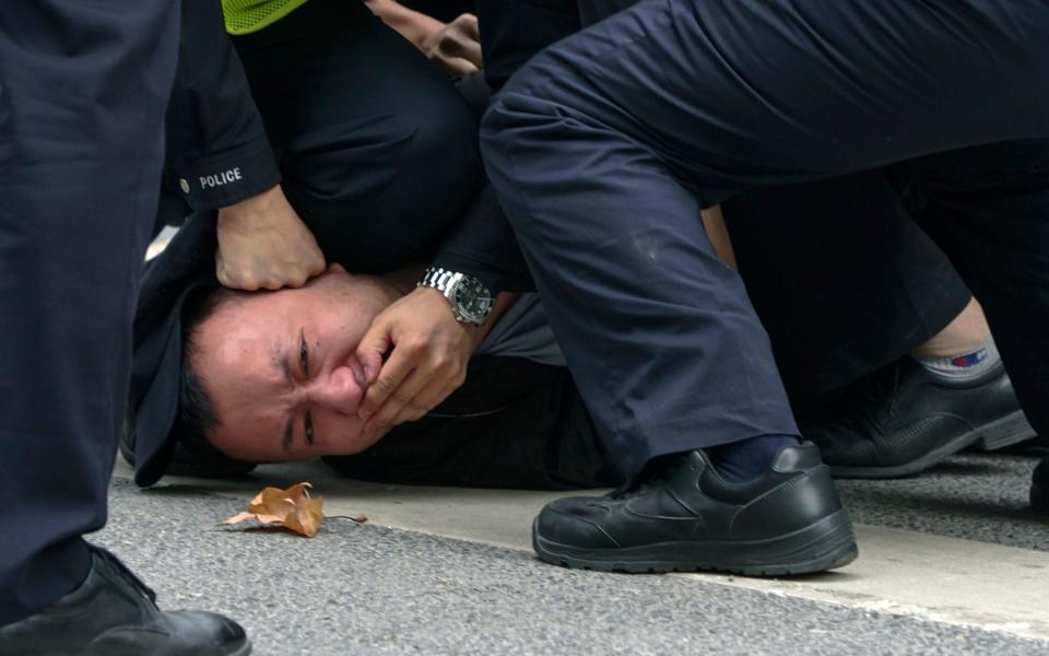 In this photo taken on Sunday, Nov. 27, 2022, policemen pin down and arrest a protester during a protest on a street in Shanghai, China - Anonymous