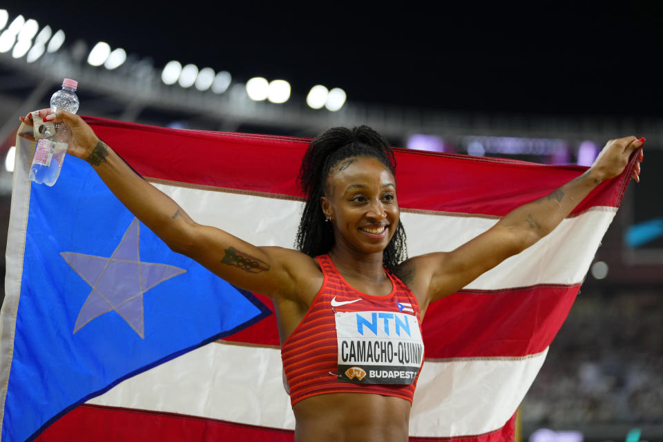 La puertorriqueña Jasmine Camacho-Quinn posa con su bandera tras conseguir la plata en los 100 metros con vallas durante el Mundial de atletismo en Budapest, el jueves 24 de agosto de 2023 (AP Foto/Petr David Josek)