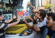 Demonstrators point to the bus fare posted on a bus, during a protest in Rio de Janeiro, Brazil, Monday, Feb.10, 2014. Anti-government protests erupted across Brazil last June, hitting their peak as 1 million Brazilians took to streets on a single night, calling for better schools and health care and questioning the billions spent to host this year's World Cup and the 2016 Olympics. The protests have since diminished in size, but remain violent. (AP Photo/Leo Correa)