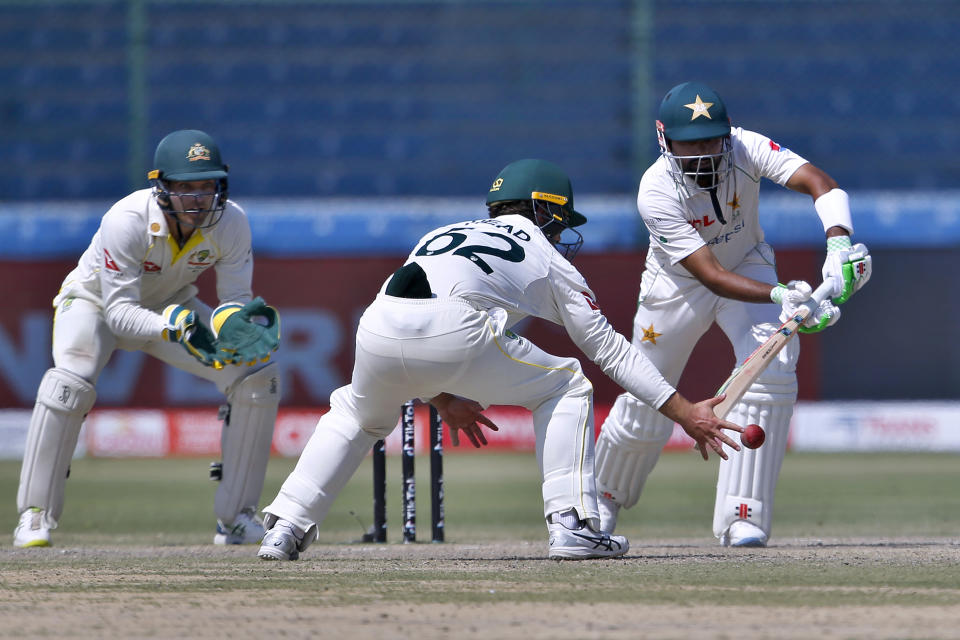 Australia's Travis Head, center, attempts to take a catch of Pakistan's Babar Azam, right, on the fifth day of the second test match between Pakistan and Australia at the National Stadium in Karachi Pakistan, Wednesday, March 16, 2022. (AP Photo/Anjum Naveed)