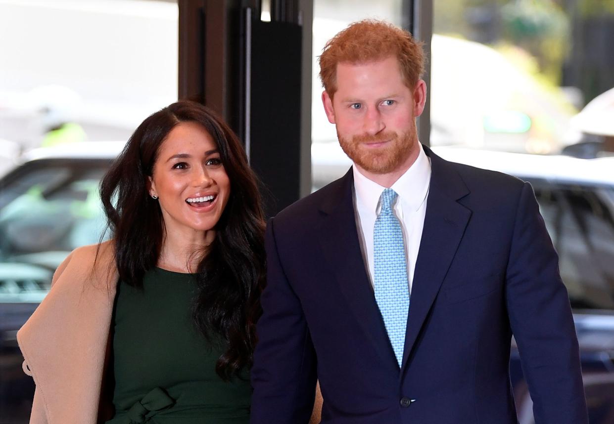Meghan Markle and Prince Harry smile holding hands