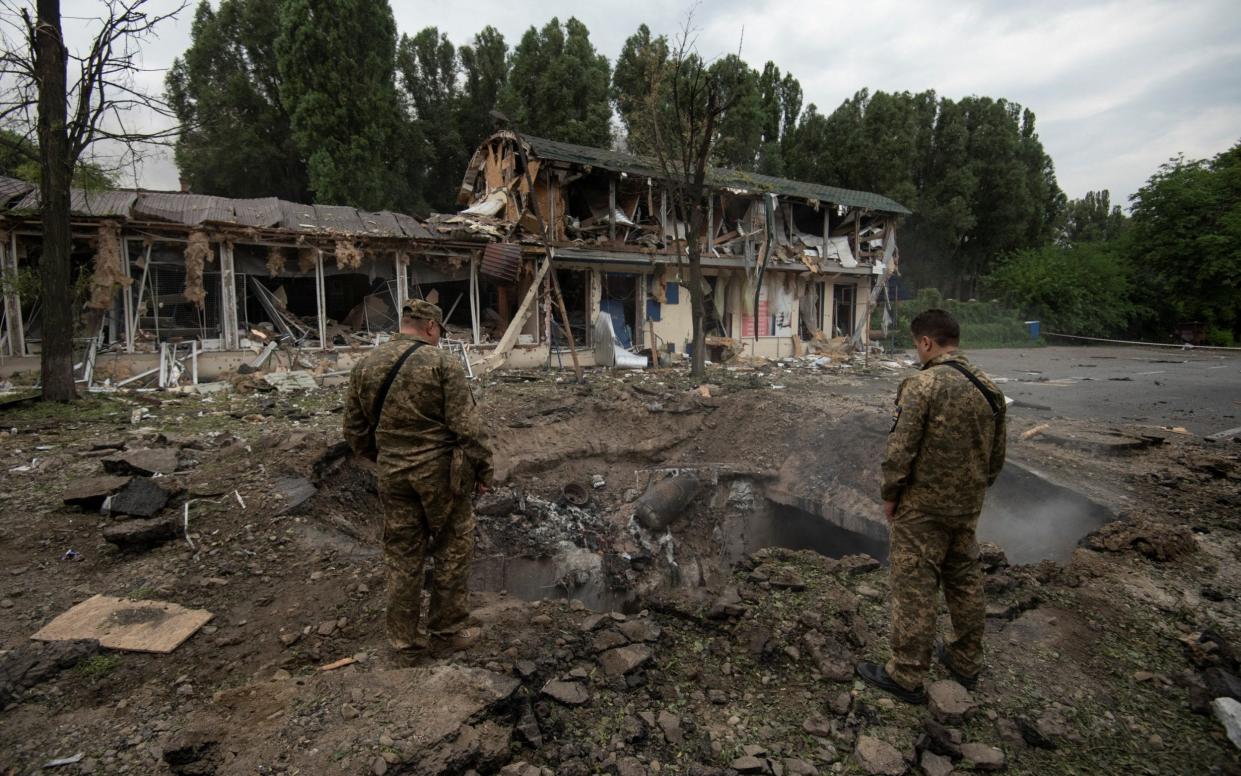 Ukrainian service members inspect a crater left by a Russian missile strike in Dnipro on 16 July - Reuters