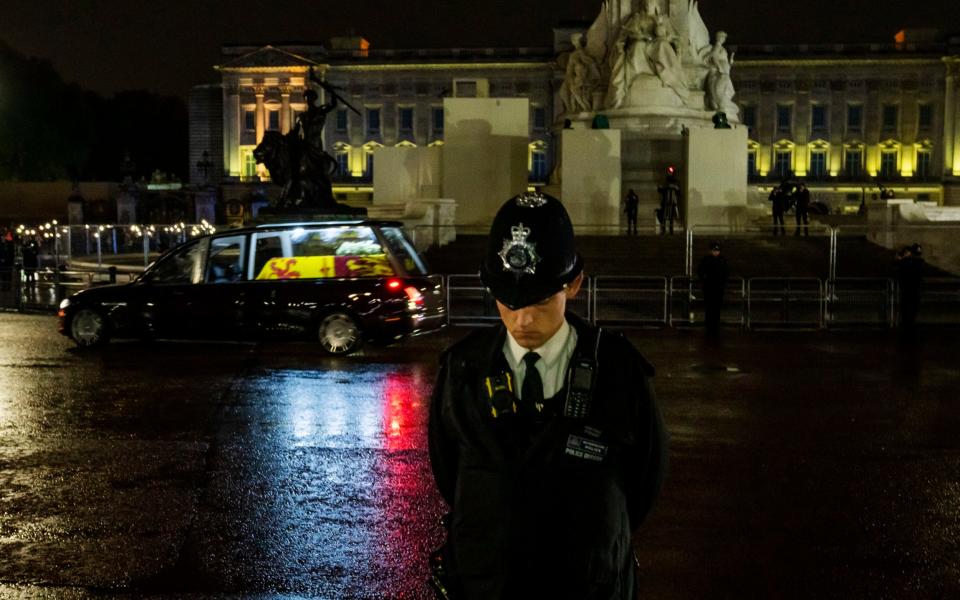 A police officer bows his head as the cortege passes - Nariman El-Mofty/AP