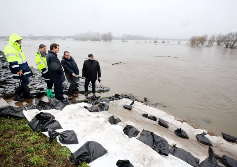 North Rhine-Westphalia's Environment Minister Oliver Krischer (2-R), together with Oberhausen's Lord Mayor Daniel Schranz (R) and firefighters at the secured Ruhr dyke on site to find out about the situation. With the support of the Duisburg fire department and the THW, extensive measures have been initiated to secure the dyke. The situation on the smaller rivers in North Rhine-Westphalia remains tense. Roland Weihrauch/dpa