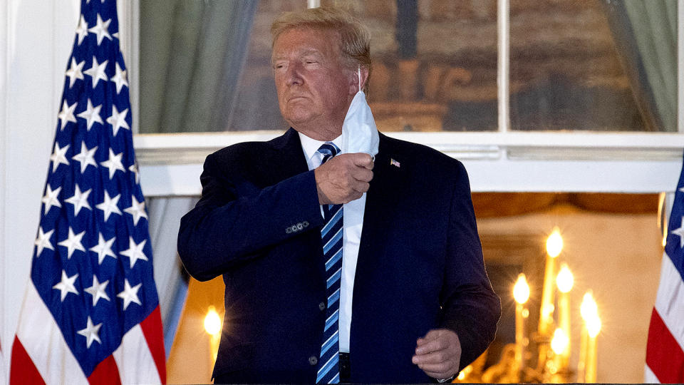 President Trump removes his mask upon return to the White House from Walter Reed National Military Medical Center on Monday. (Win McNamee/Getty Images)