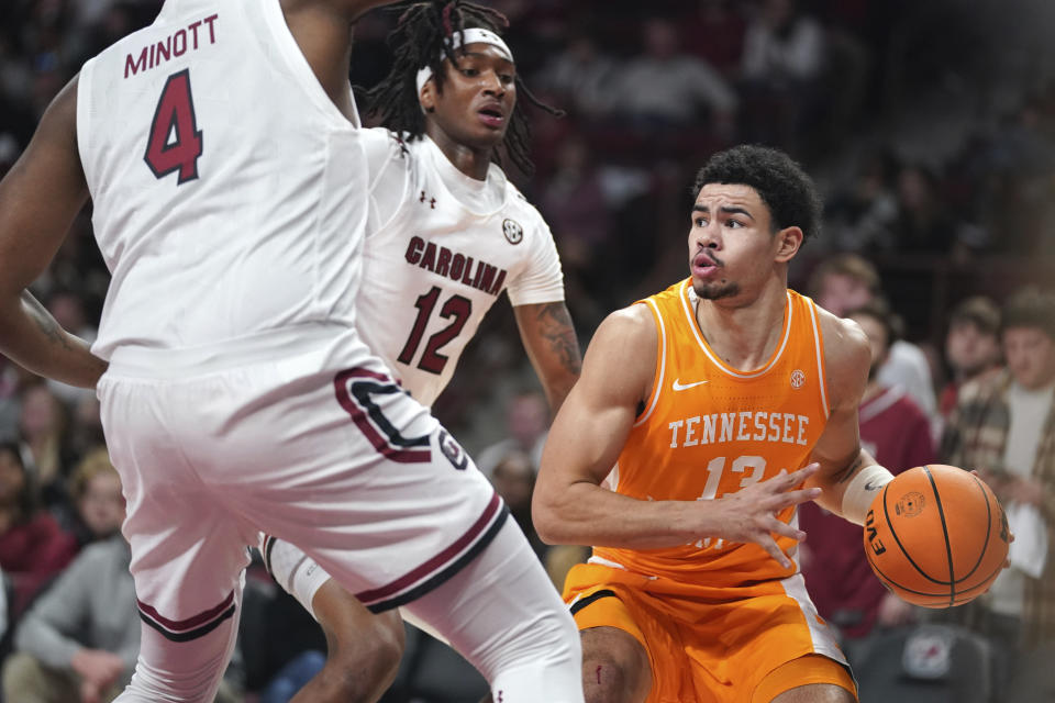 Tennessee forward Olivier Nkamhoua (13) is defended by South Carolina guard Zachary Davis (12) and Tre-Vaughn Minott (4) during the first half of an NCAA college basketball game Saturday, Jan. 7, 2023, in Columbia, S.C. (AP Photo/Sean Rayford)
