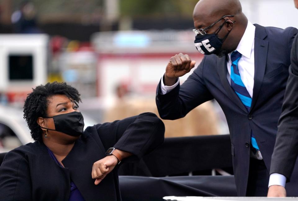 FILE - Sen. Raphael Warnock, right, bumps elbows with Stacey Abrams during a campaign rally with U.S. President-elect Joe Biden at Pullman Yard on Dec. 15, 2020 in Atlanta, Georgia.