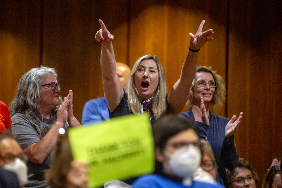 FILE - Amy Facchinello, a Grand Blanc school board member, cheers on a parent who spoke against the county's K-6 school mask mandate during public comment as more than 100 people pack the Harris Auditorium at a Genesee County Board of Commissioners meeting on Monday, Aug. 30, 2021, at the county administration building in downtown Flint, Mich. Attorney General Dana Nessel has charged 16 Republicans Tuesday, July 18, 2023, with multiple felonies after they are alleged to have submitted false certificates stating they were the state’s presidential electors despite Joe Biden’s 154,000-vote victory in 2020. The group includes Republican National Committeewoman Kathy Berden, Meshawn Maddock, former co-chair of the Michigan Republican Party, and Facchinello. (Jake May/The Flint Journal via AP)