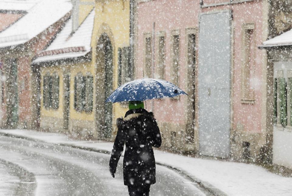 <p>Eine Frau in Bamberg trägt einen Regenschirm, um sich vor dem starken Schneefall zu schützen. (Bild: Nicolas Armer/AP) </p>