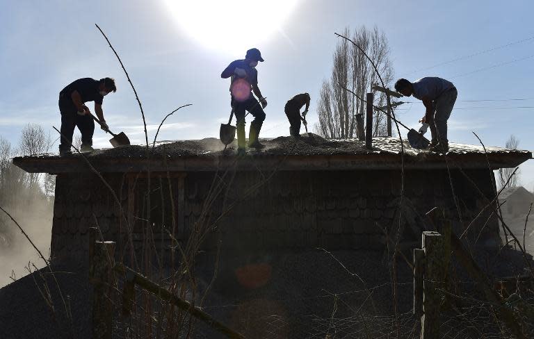 Men shovel ash off of the roof of a house in La Ensenada, Chile, on April 24, 2015