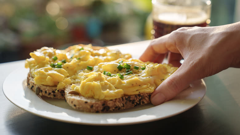 Holding scrambled eggs on toast