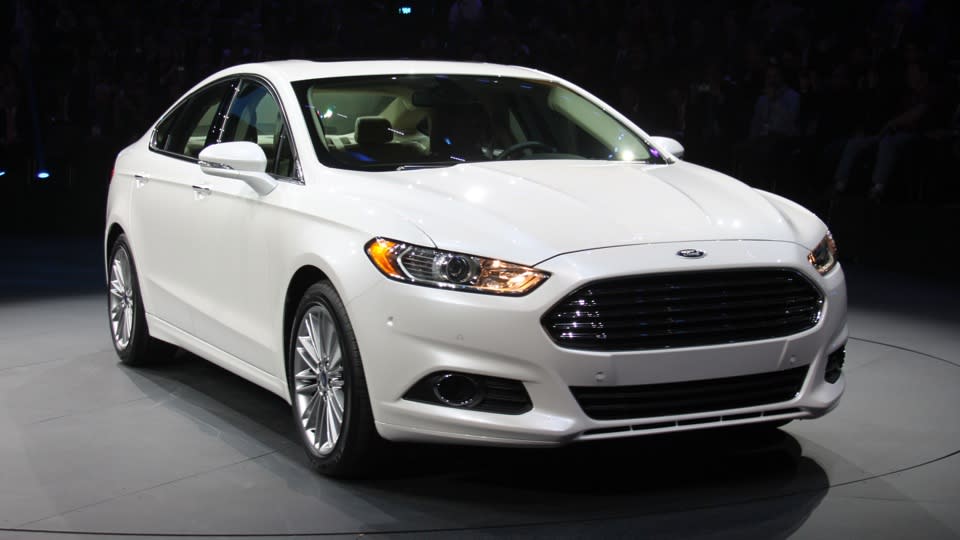 Later this year, Ford Motor Co. will launch this: the 2013 Ford Fusion midsize sedan in three variations — including a plug-in hybrid that gets 100 mpg, besting every other liquid-powered vehicle for sale to the American public. It could be a winning equation, but there's a few key variables Ford hasn't revealed. The current Fusion has turned into a mainstay of Ford's lineup, and the most popular car built by an American automaker, with sales hitting 248,067 in 2011. For its redesign, Ford will run the same play it's called on with the smaller Fiesta and Focus −- build one version of the Fusion for sale worldwide, using the Mondeo name in Europe and elsewhere, to lower costs while raising quality. Assembled in Mexico and Michigan, styled in Europe to follow the new Ford global look, two of its three engines will be built in Spain and England.