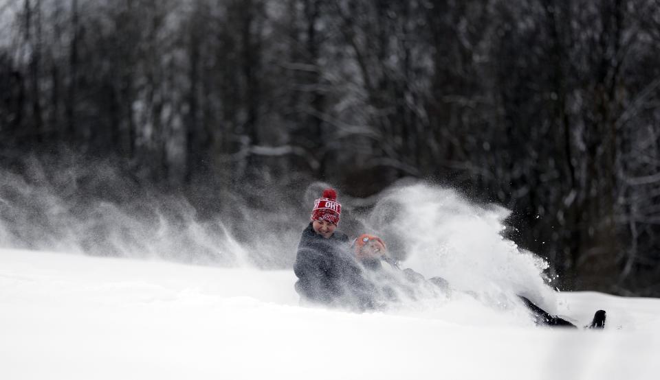 Haley Milne and Dan Carroll fly down the hill on their sled at Reid Middle School in Pittsfield, Mass., on Saturday, Dec. 17, 2016. A winter storm of snow, freezing rain and bone-chilling temperatures hit the nationss mid-section and East Coast on Saturday. (Stephanie Zollshan/The Berkshire Eagle via AP)