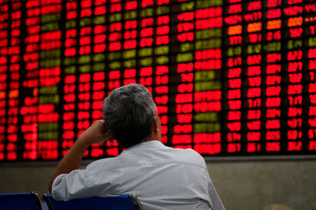 FILE PHOTO: An investor looks at an electronic board showing stock information at a brokerage house in Shanghai, China September 7, 2018. REUTERS/Aly Song/File Photo