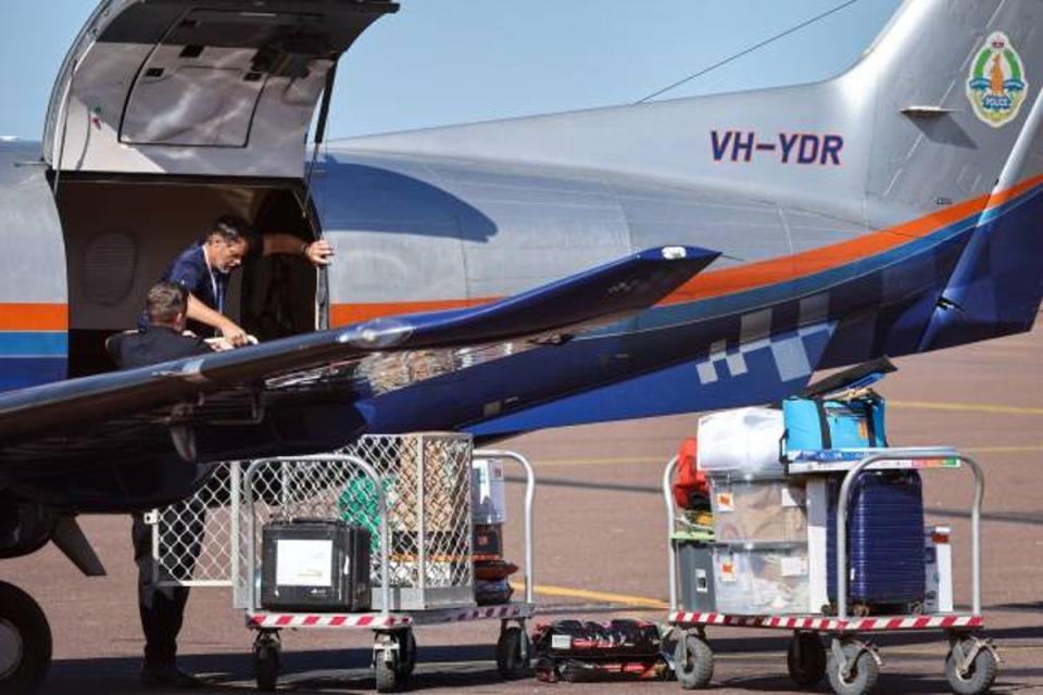 Police personnel load equipments onto a Northern Territory Police plane on the tarmac of the Darwin International Airport in Darwin on 28 August 2023 (AFP via Getty Images)