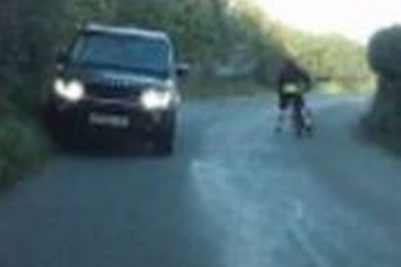 A vehicle coming close to hitting a cyclist on a road