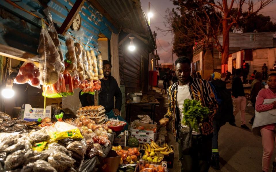 Bulbs illuminate a food stall in the Imizamo Yethu informal settlement in the Hout Bay district of Cape Town, South Africa - Dwayne Senior/Bloomberg