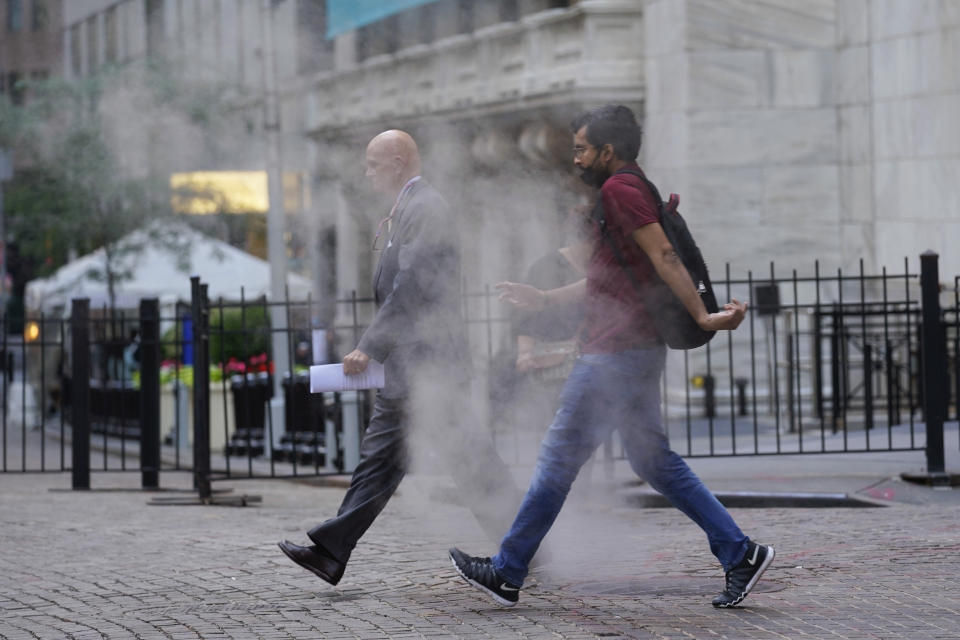 FILE - In this June 16, 2021 file photo, people walk through steam from a street grating during the morning commute in New York. Companies around the U.S. are scrambling to figure out how to bring employees back to the office after more than a year of them working remotely. Most are proceeding cautiously, trying to navigate declining COVID-19 infections against a potential backlash by workers who are not ready to return. (AP Photo/Richard Drew)