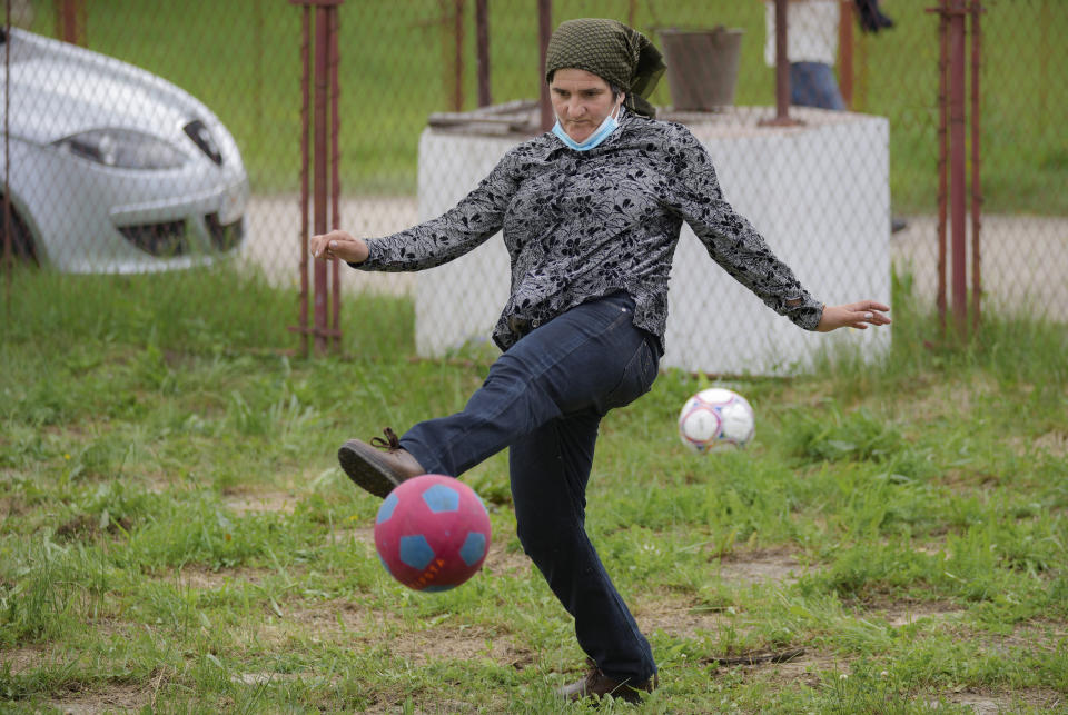 A woman kicks a ball after she took her children for an eyesight examination performed by volunteer ophthalmologists, in Nucsoara, Romania, Saturday, May 29, 2021. (AP Photo/Vadim Ghirda)