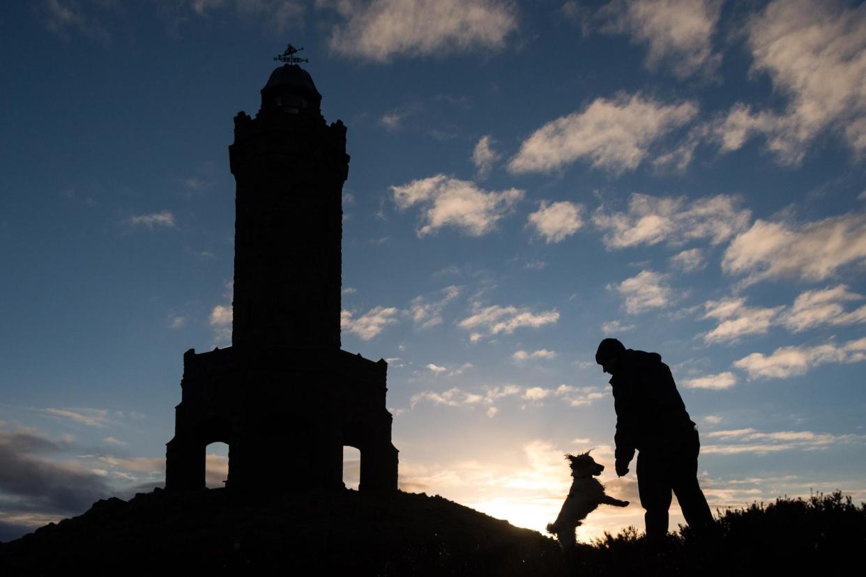 A dog walker watches the sunrise on Blackburn hill. The region could see tighter restrictions introduced following a spike in coronavirus cases: PA