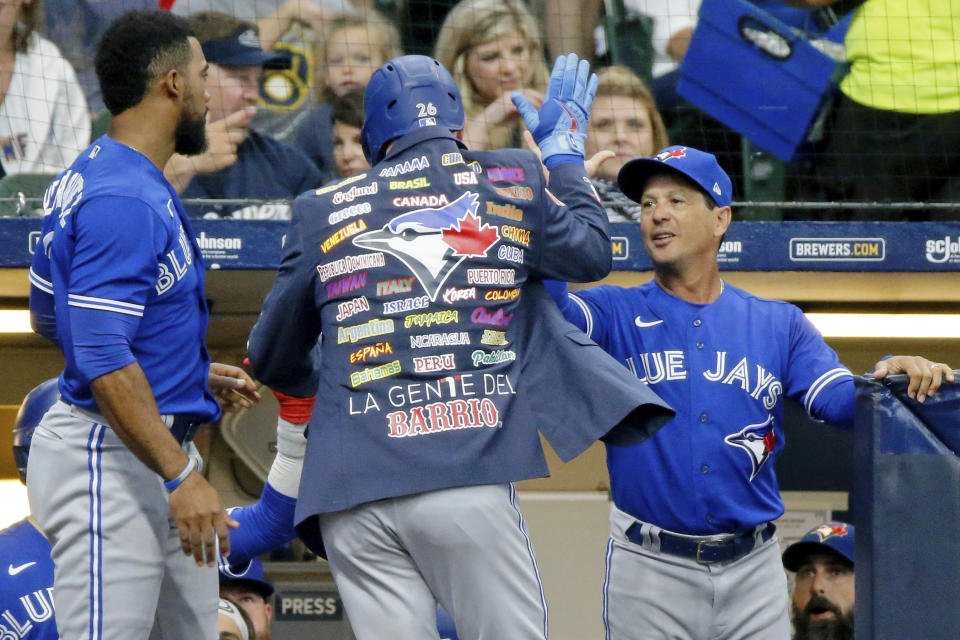 Toronto Blue Jays' Matt Chapman, center, is congratulated by manager Charlie Montoyo, right, after hitting a solo home run against the Milwaukee Brewers during the fifth inning of a baseball game Saturday, June 25, 2022, in Milwaukee. (AP Photo/Jon Durr)