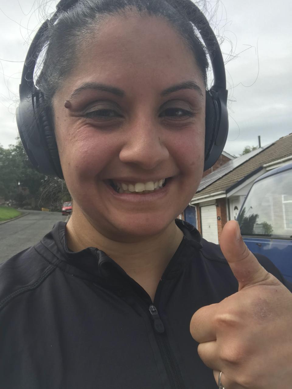 Sanam Saleh gives a thumbs up while wearing a running top and headphones