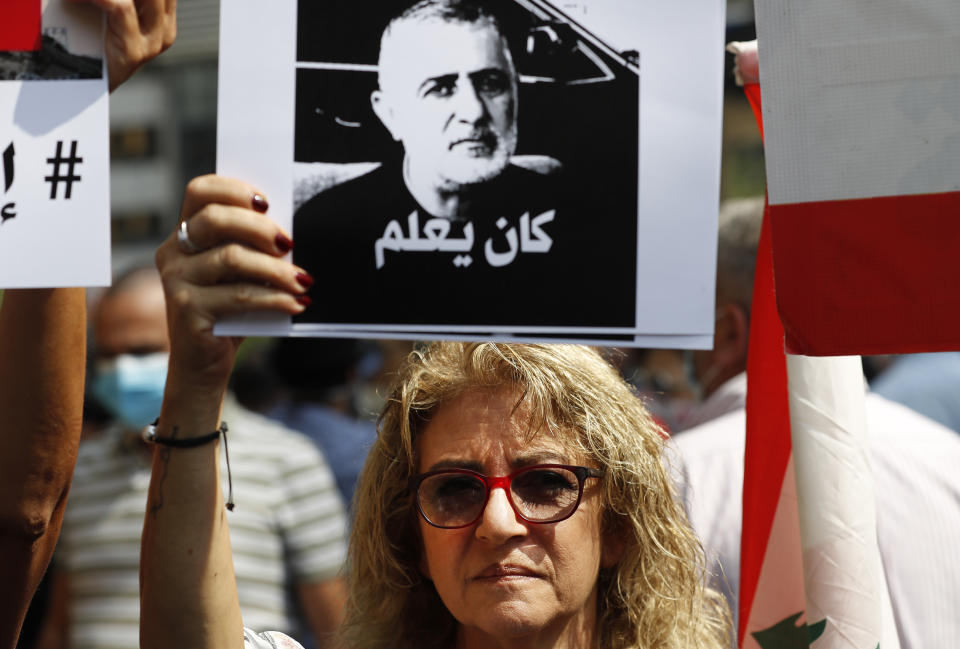 A protester holds a portrait Wafiq Safa, a top Hezbollah security official, with Arabic that reads: "He knew," during a demonstration of solidarity with Judge Tarek Bitar who is investigating last year's deadly seaport blast, in Beirut, Lebanon, Wednesday, Sept. 29, 2021. Hundreds of Lebanese, including families of the Beirut port explosion victims, rallied Wednesday outside the court of justice in support of Bitar after he was forced to suspend his work. Bitar is the second judge to take on the complicated investigation. (AP Photo/Hussein Malla)