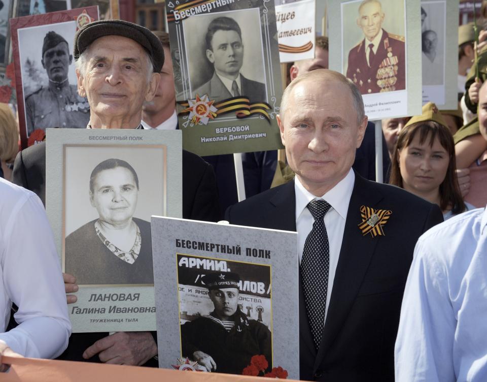 FILE In this file photo taken on Thursday, May 9, 2019, Russian President Vladimir Putin, right, holds a portrait of his father Vladimir Spiridonovich Putin, in front of him, during the Immortal Regiment march through Red Square celebrating 74 years since the victory in WWII in Red Square in Moscow, Russia. Russian President Vladimir Putin has ordered the postponement of a Victory Day parade marking the 75th anniversary of the end of World War II, citing the ongoing public health threat from the coronavirus pandemic. Speaking in televised remarks on Thursday, April 16, 2020, Putin said the festivities would be held later this year. (Alexei Druzhinin, Sputnik, Kremlin Pool Photo via AP, File)