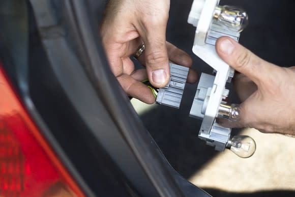 A person replacing a vehicle light bulb component.