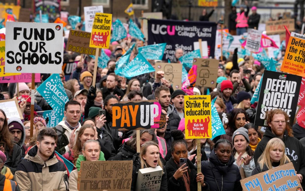 Thousands of demonstrators wave banners as they stand near Downing Street in Westminster in London - Kirsty Wigglesworth/AP