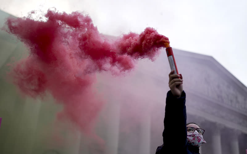 A demonstrator holds a flare during a protest