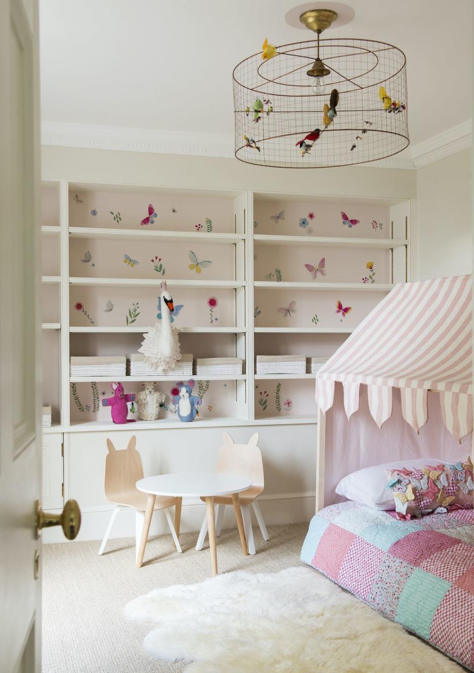 <p>We love how wallpaper has been used to create a design feature in this shelving. It really adds a decorative touch when you peek through the doorway and the pretty colours make it easy to accessorise the rest of the room. The combination of stripes and checks works really well too for a girls' bedroom, and adding a tactile element like the sheepskin rug is a great idea for young children as touch is so important.</p><p>Pictured: Hyde Park Gate project, <a href="https://www.kellingdesigns.com" rel="nofollow noopener" target="_blank" data-ylk="slk:Kelling Designs;elm:context_link;itc:0;sec:content-canvas" class="link ">Kelling Designs</a>. Voliéres medium birdcage chandelier, <a href="https://go.redirectingat.com?id=127X1599956&url=https%3A%2F%2Fwww.grahamandgreen.co.uk%2Fvolieres-medium-bird-cage-pendant&sref=https%3A%2F%2Fwww.housebeautiful.com%2Fuk%2Fdecorate%2Fbedroom%2Fg35589644%2Fgirls-bedroom-ideas%2F" rel="nofollow noopener" target="_blank" data-ylk="slk:Graham & Green;elm:context_link;itc:0;sec:content-canvas" class="link ">Graham & Green</a></p>