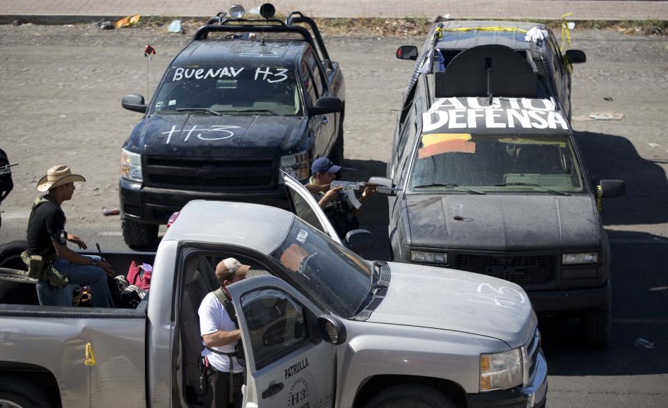 Integrantes del Consejo de Autodefensa de Michoacán vigilan desde sus camionetas la entrada al poblado de Nueva Italia, México, el lunes 13 de enero de 2014. Grupos de civiles armados están redoblando su ofensiva contra narcotraficantes en el estado de Michoacán. (Foto AP/Eduardo Verdugo)