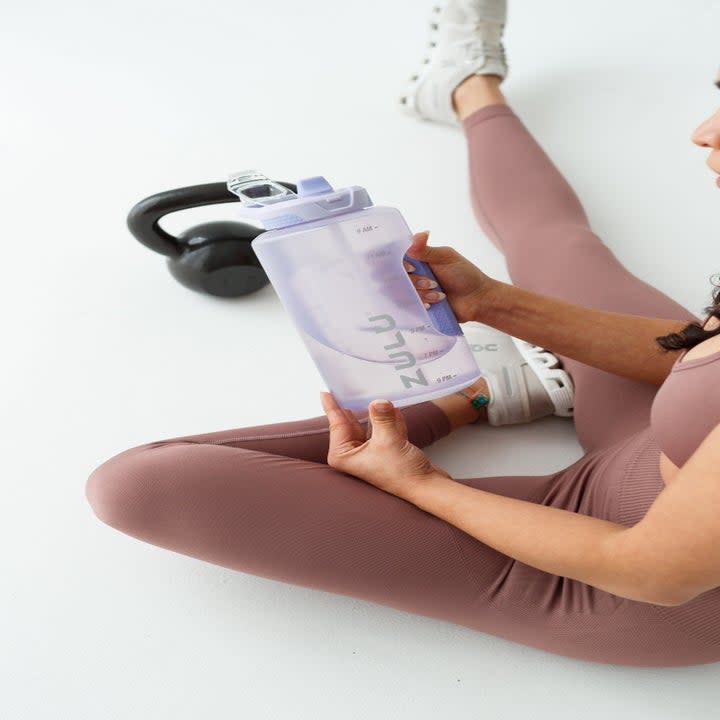 a model holding the water bottle bottle in purple