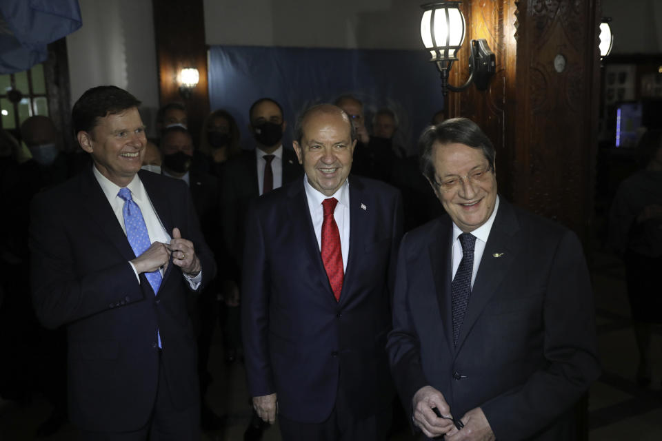 Cyprus' Greek Cypriot President Nicos Anastasiades, right, Ersin Tatar, leader of the breakaway Turkish Cypriots, center, and Colin Stewart, the new head of the United Nations peacekeeping mission smile during their meeting on the ethnically divided island nation, talks during their meeting in Ledra Palace abandoned hotel inside the U.N. controlled buffer zone that cuts through the capital Nicosia, on Tuesday, Dec. 14, 2021. The meeting is billed primarily as a social event geared toward breaking the ice between the two leaders in the absence of formal talks that have been at a standstill since the last bid to reach a reunification agreement collapsed in the summer of 2017. (Yiannis Kourtoglou/Pool via AP)