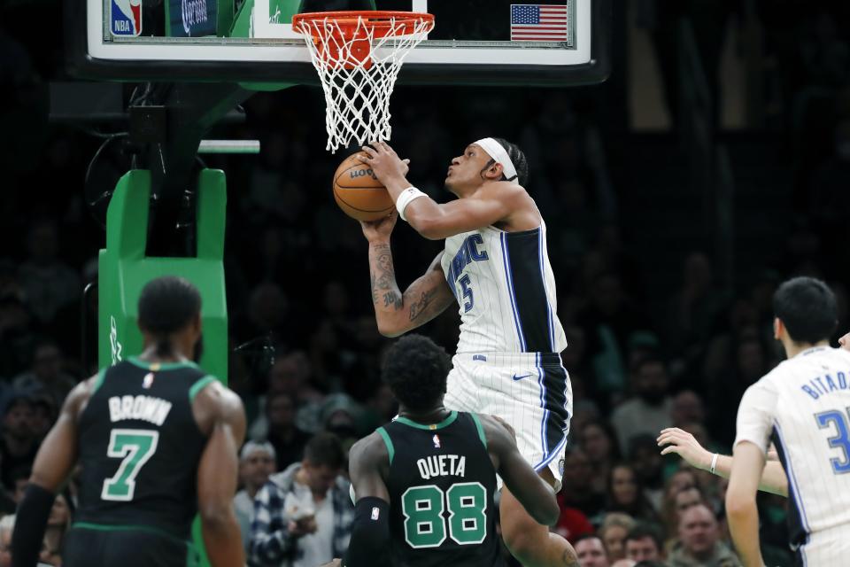 Orlando Magic's Paolo Banchero (5) shoots front of Boston Celtics' Neemias Queta (88) and Jaylen Brown (7) during the first half of an NBA basketball game Friday, Dec. 15, 2023, in Boston. (AP Photo/Michael Dwyer)