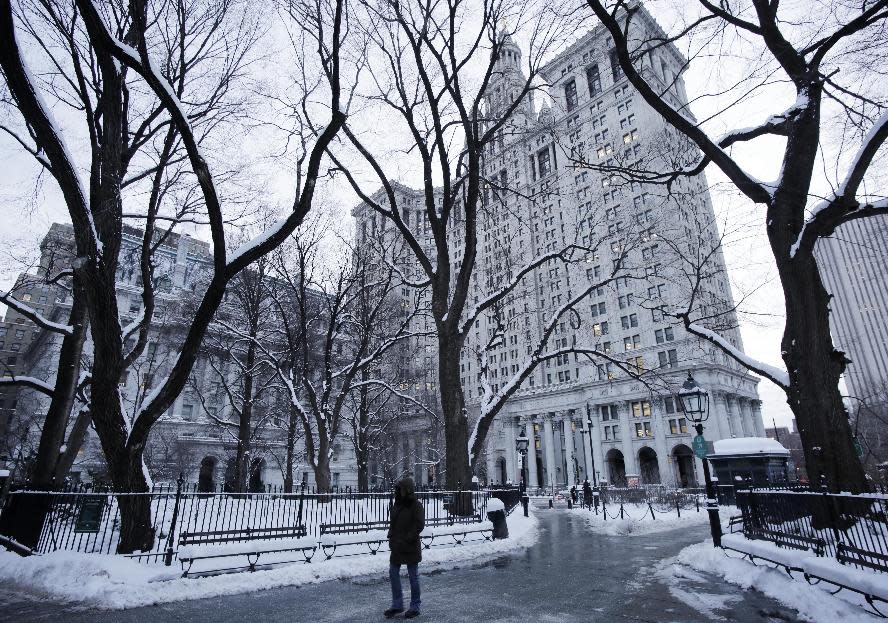 A pedestrian passes through City Hall Park and the Municipal Building, center, Wednesday, Jan. 22, 2014, in New York. The Northeast struggled to dig out of a winter storm Wednesday that swirled up the coast, disrupting government work in Washington and leaving behind bitter cold that sapped fuel supplies. (AP Photo/Mark Lennihan)