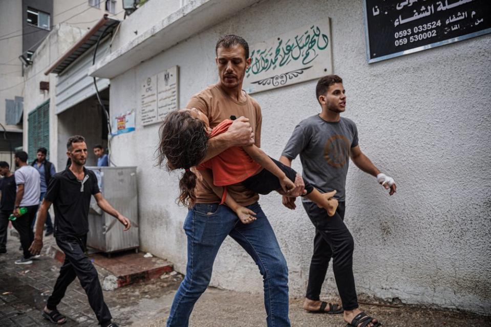 A Palestinian man carries his daughter's body near Al-Shifa hospital, Oct. 9, after she was killed by an airstrike. <span class="copyright">Saher Alghorra—Zuma Press</span>