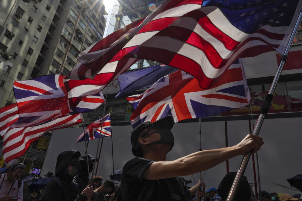 Protesters holding flags of the U.S. and Britain march toward the Tsim She Tsui police station during a rally in Hong Kong, Sunday, Oct. 20, 2019. Hong Kong protesters again flooded streets on Sunday, ignoring a police ban on the rally and demanding the government meet their demands for accountability and political rights. (AP Photo/Vincent Yu)