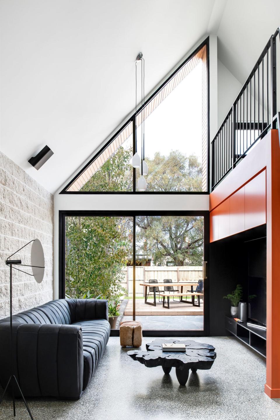 The living room wall was originally meant to be covered in plywood, but Wesley went with a bright orange instead to “drag you into the space and make you feel welcome,” he says.