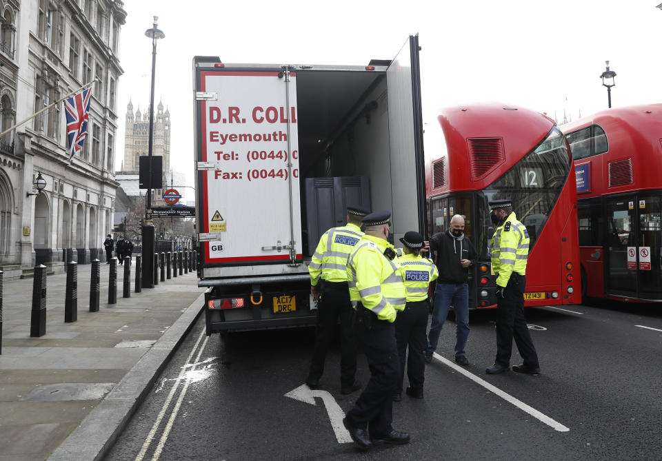 Police speak to a shellfish export truck driver as he is stopped for an unnecessary journey in London, Monday, Jan. 18, 2021, during a demonstration by British Shellfish exporters to protest Brexit-related red tape they claim is suffocating their business. The drivers were later stopped by police and issued with fines for an 'unnecessary journey' due to the national lockdown to curb the spread of the coronavirus. (AP Photo/Alastair Grant)