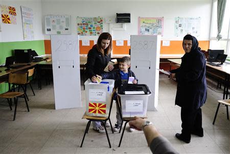 A boy casts ballots for his mother during presidential and early parliamentary elections in Skopje April 27, 2014. REUTERS/Ognen Teofilovski