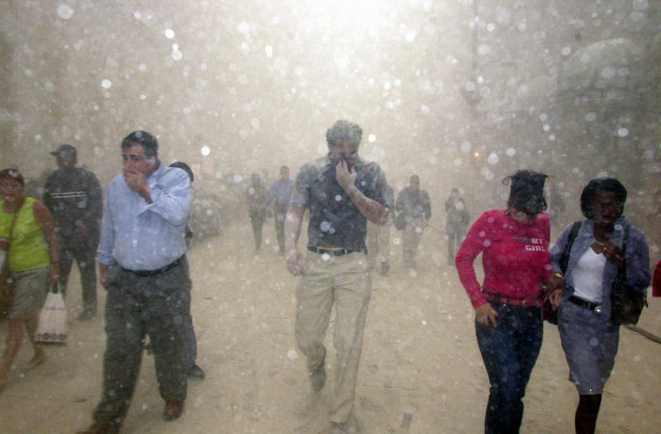 People run from the collapse of World Trade Center towers in New York, Tuesday, Sept. 11, 2001 after terrorists crashed two hijacked airliners into the World Trade Center and brought down the twin 110-story towers. (AP Photo/Suzanne Plunkett)